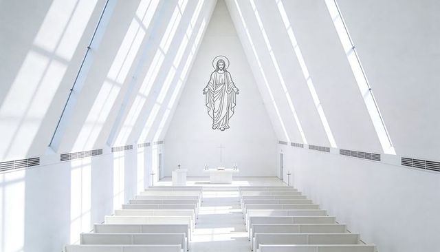 Minimalist modern chapel interior with sunlit pews and line drawing of jesus above altar