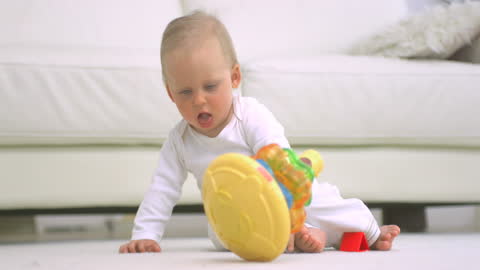 Adorable Baby in White Onesie Playing with Colorful Toy on Floor