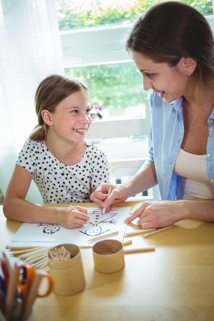 Smiling mother and daughter drawing together at home