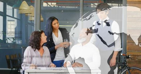 Discussing global strategy around desk in bright modern coworking office with map overlay