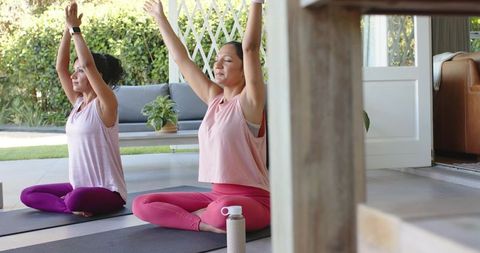 Two women practicing morning patio yoga in pink activewear for mindfulness and wellness