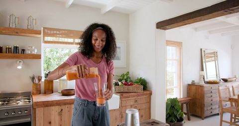Smiling Woman Pouring Fresh Juice in Rustic Kitchen