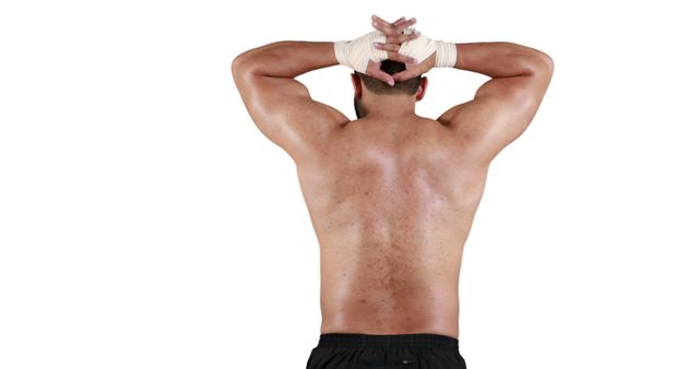 Muscular man with wrapped hands seen from behind stretching. Useful for fitness and wellness advertisements, strength training blogs, and promotional material for gyms and personal trainers.