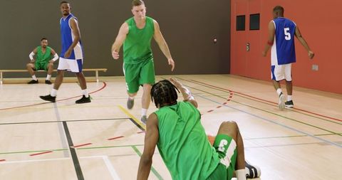 Indoor basketball action with defender pressuring while player dribbling crossover and falling