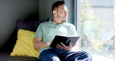 Mature Man Reading by Sunlit Window in Modern Home