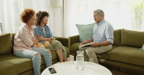 Multigenerational family counseling discussing concerns on sofa with therapist taking notes