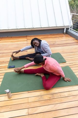 African american couple stretching on rooftop deck for outdoor fitness and wellness