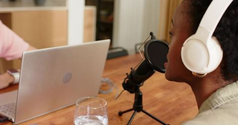 Podcast recording with african american woman wearing headphones speaking into microphone