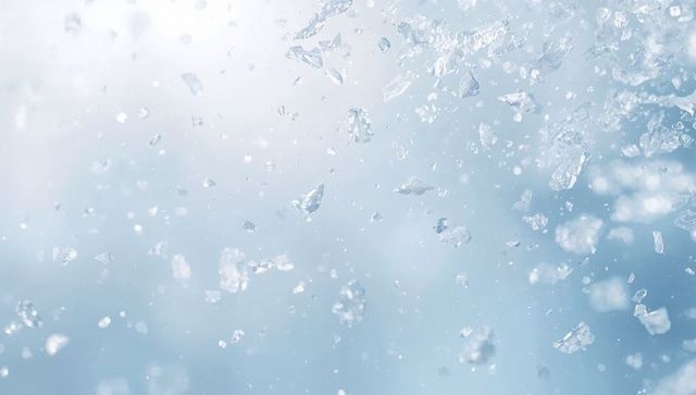Glittering ice crystals floating in soft blue bokeh background for winter design