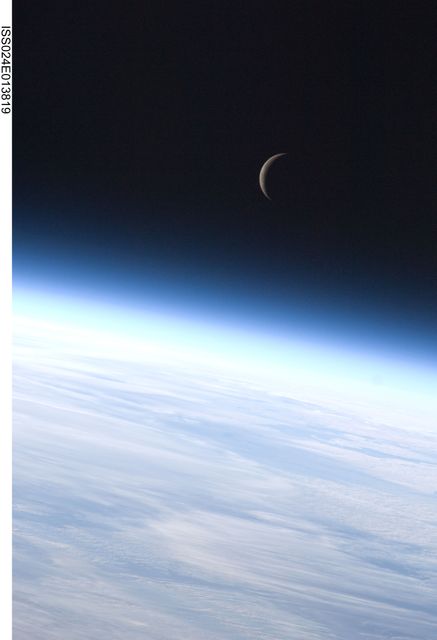 Crescent moon illuminated over the curvature of Earth's atmosphere, as seen from the International Space Station. Ideal for use in presentations about space exploration, astronomy, and the beauty of our solar system. This photograph captures the vastness of space and can be used in educational materials to demonstrate the view from space.