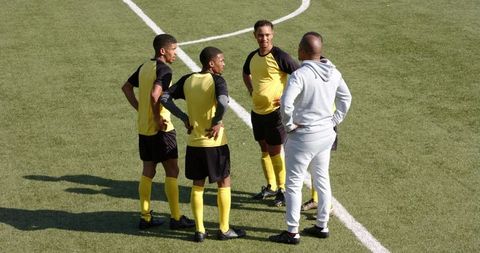 Soccer coach strategizing with team on field during practice session