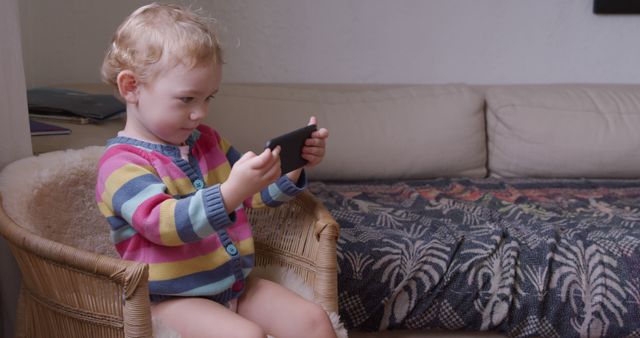 Cute Toddler Sitting in Chair, Playing with Smartphone - Download Free Stock Images Pikwizard.com