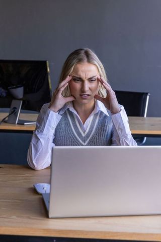 Stressed Woman Frowning at Laptop in Modern Office