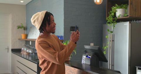 African American man scanning smartphone at modern cafe counter for contactless payment