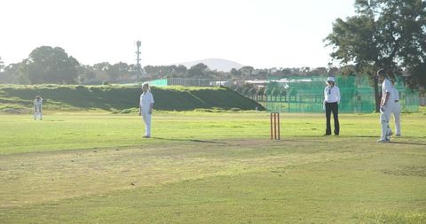 Women playing outdoor cricket match under bright sunlight