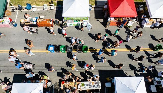 Aerial market showing crowd walking between vendor tents at colorful outdoor street fair