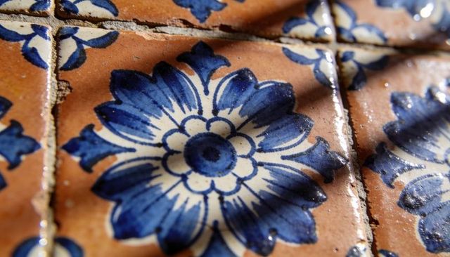 Cobalt blue floral ceramic tile close-up showing glazed pattern, grout, chips and texture