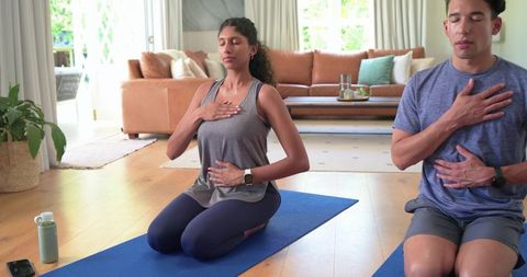 African american couple practicing breathwork and mindful breathing in sunlit living room