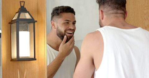 Man grooming and admiring beard in modern bathroom