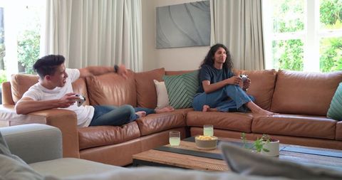 African american couple playing console games on sunlit leather sofa