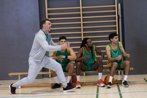 Excited basketball coach shouting instructions to focused team