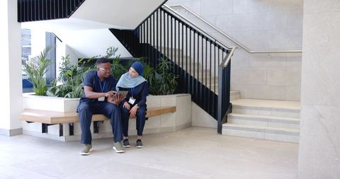 Healthcare professionals consulting on tablet in contemporary hospital lobby with plants