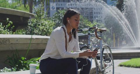 Businesswoman Relaxing by Urban Fountain with Bicycle