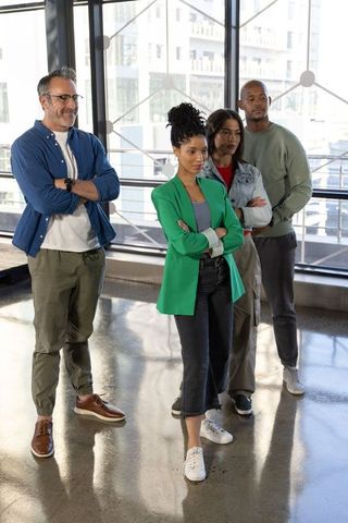 Diverse team posing confidently in modern office with female leader wearing green blazer