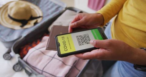 Packing for Travel Holding COVID-19 Passport on Smartphone