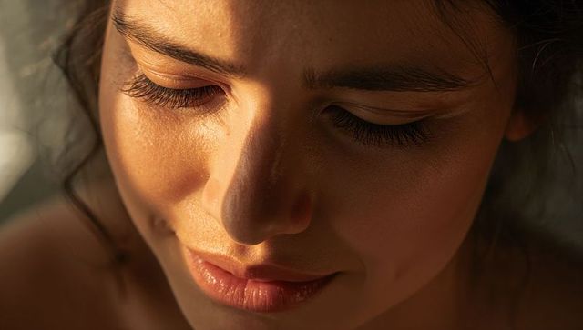 Gazing woman smiling with closed eyes in warm golden hour close-up portrait