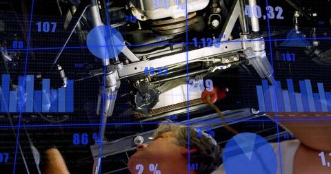 Mechanic repairing vehicle undercarriage while hud diagnostic overlays displaying charts