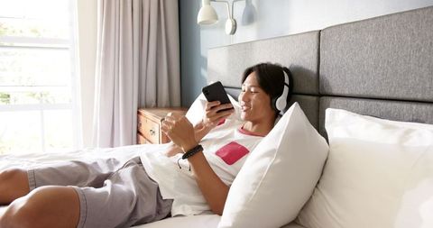 Teen Relaxing in Comfort Listening to Music on Smartphone