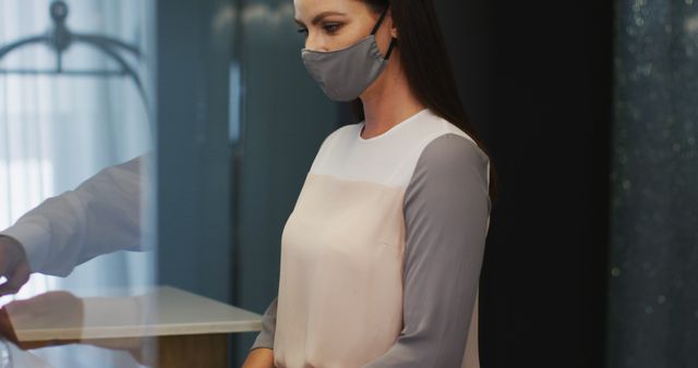 Caucasian woman wearing grey face mask looking at the camera and smiling. out and about during coronavirus covid 19 pandemic.