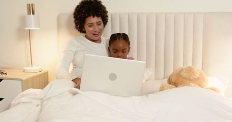 Mother and Daughter Bonding Over Laptop in Cozy Bedroom