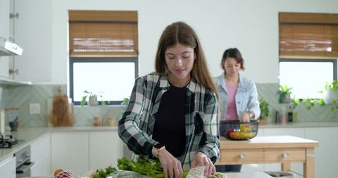 Young women preparing fresh vegetables on kitchen island for healthy home cooking