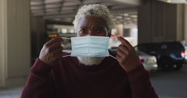 Portrait of african american senior man wearing face mask in the parking lot. hygiene and social distancing during coronavirus covid-19 pandemic.