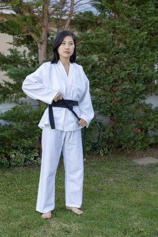 Asian Woman in Gi Adjusting Black Belt Outdoors