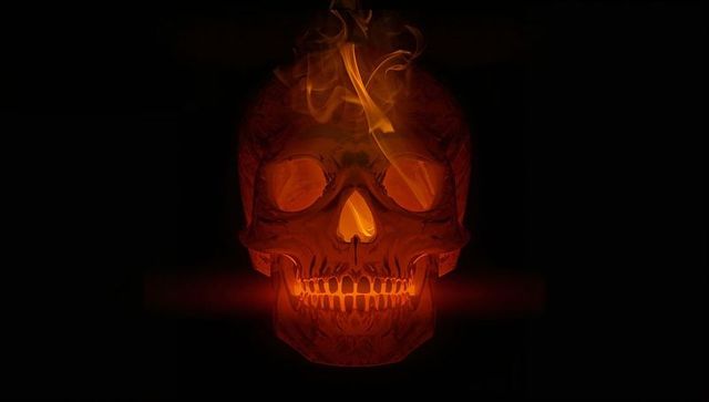 Glowing skull fiery interior with flames and smoke in dark void