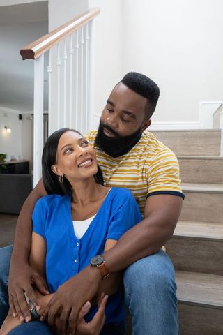 Diverse Couple Embracing on Wooden Staircase Displaying Love and Elegance