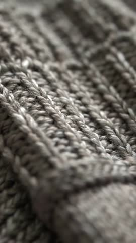Vertical panning over gray knit showing rib and cable texture for tactile backgrounds
