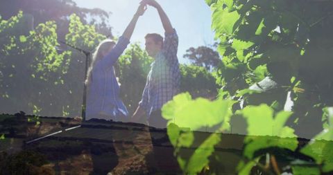 Couple twirling through sunlit vineyard leaves double exposure rustic romance