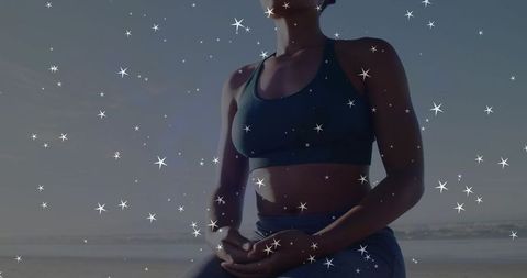 Meditating woman on coastal beach at sunrise with star overlay for mindful calm
