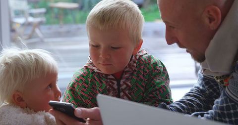 Father and Children Engaging with Smartphone Indoors