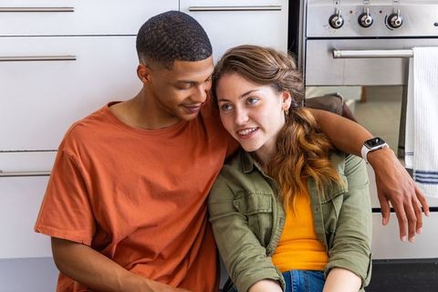 Interracial couple cuddling on kitchen floor sharing warm cozy domestic lifestyle moment