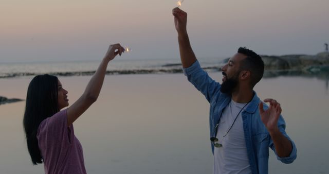 Couple celebrating with sparklers on beach at sunset - Download Free Stock Images Pikwizard.com