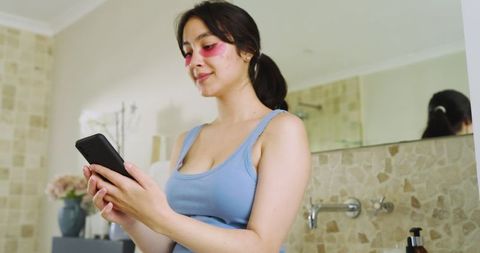 Woman relaxes with skincare routine and smartphone