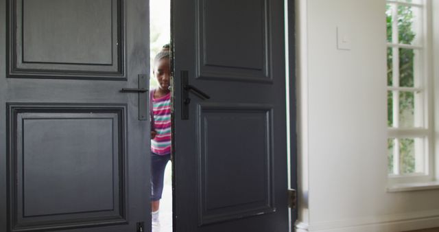 Image of african american girl with schoolbag opening front door, coming home from school. Childhood and domestic life.