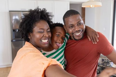 African american family taking playful selfie in bright modern kitchen, smiling together