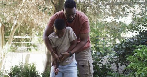 Father Teaching Son Golf in Sunlit Backyard Garden