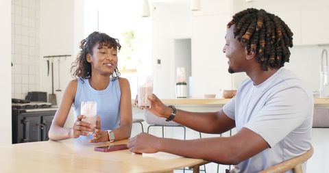 African american couple enjoying smoothies at bright modern kitchen table casual morning chat